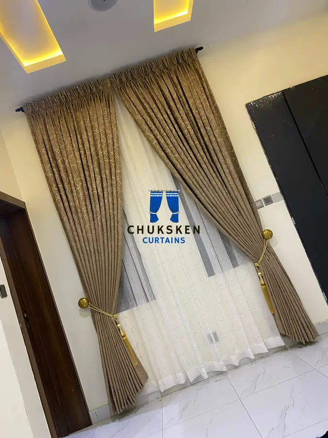 Gold curtains with tieback over sheer fabric