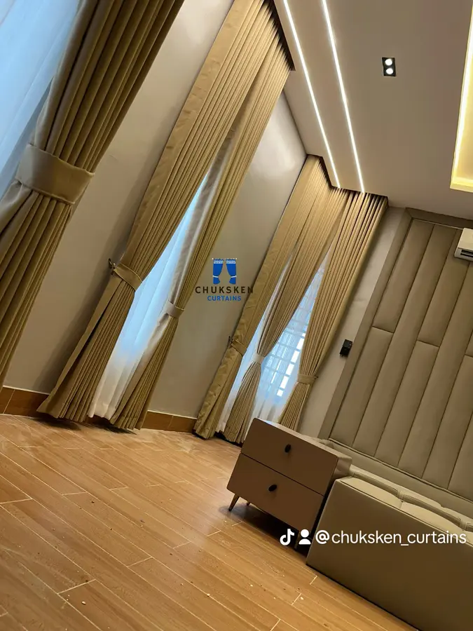 Pleated curtain with tieback in a living room, with paneled ceiling and cove lighting